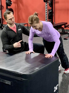 Personal trainer guiding an athlete through a corrective movement exercise