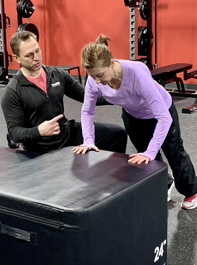 Personal trainer guiding an athlete through a corrective movement exercise